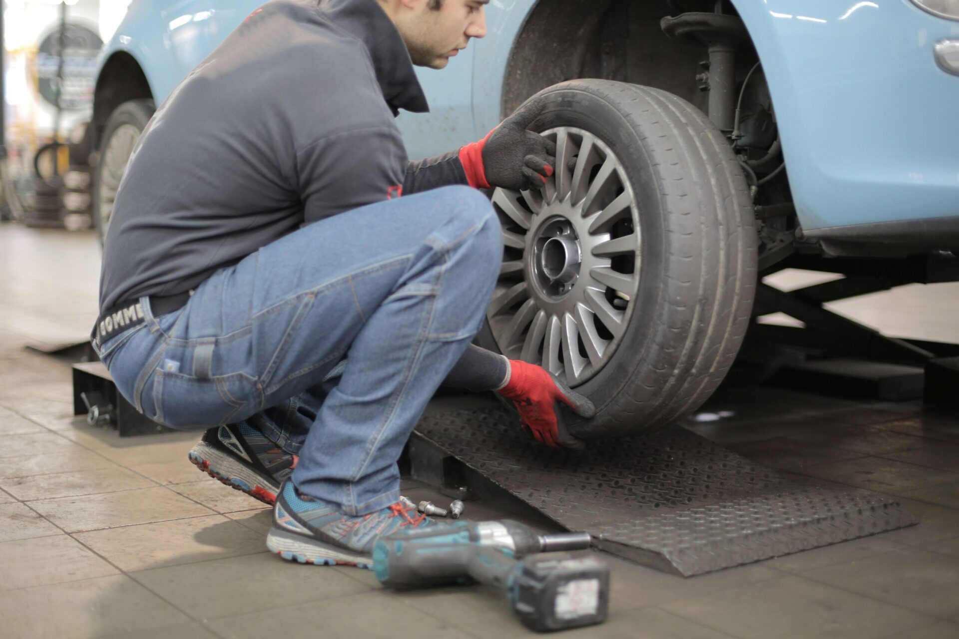 man changing a tire on a blue vehicle