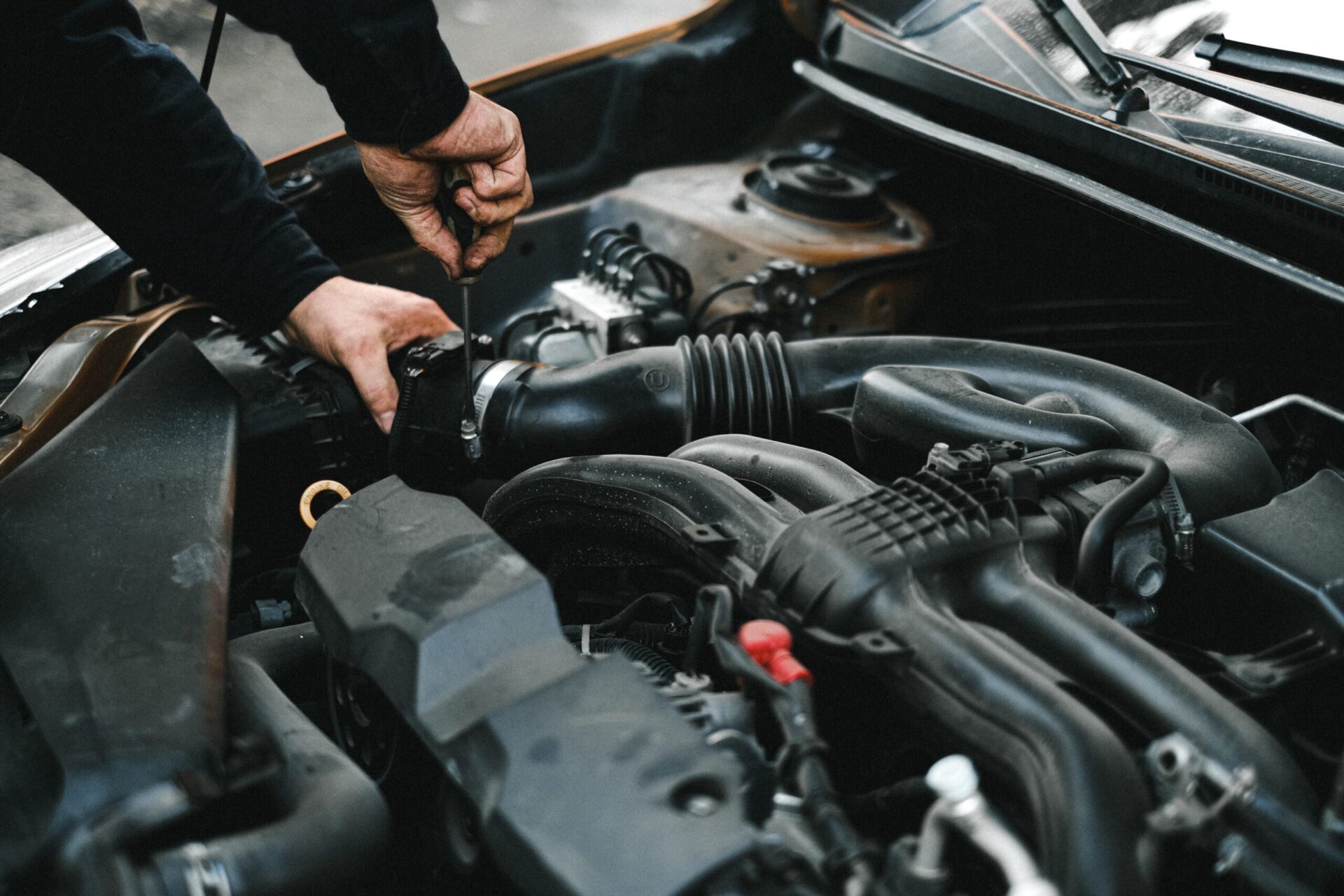 Hands Reaching Into the Engine Bay of a Car