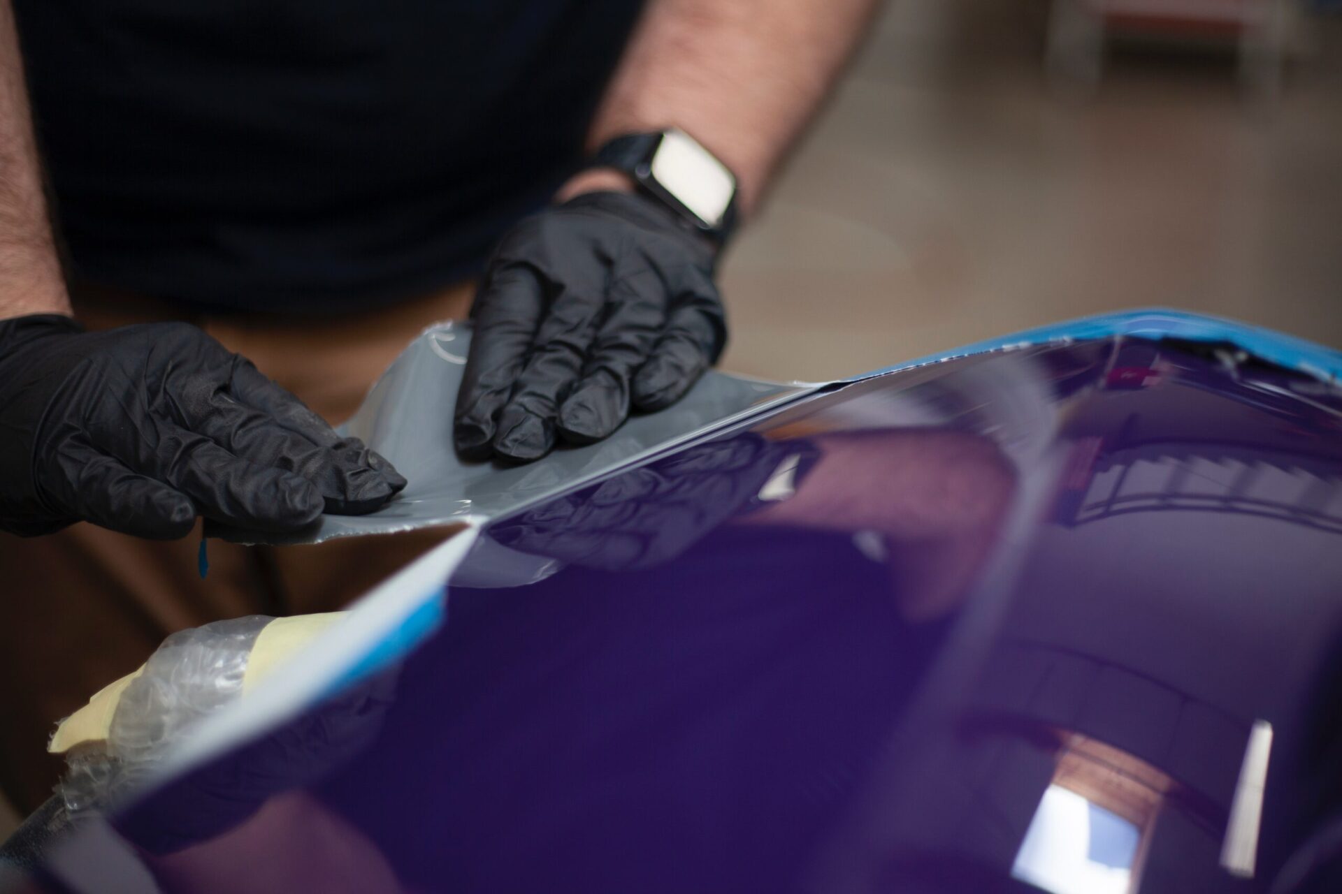 a man in black gloves waxing a blue car